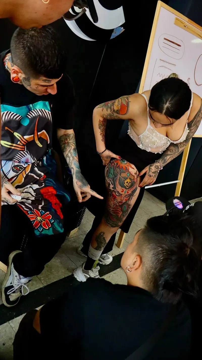 Estudiantes practicando un tatuaje sobre piel acompañados por el instructor